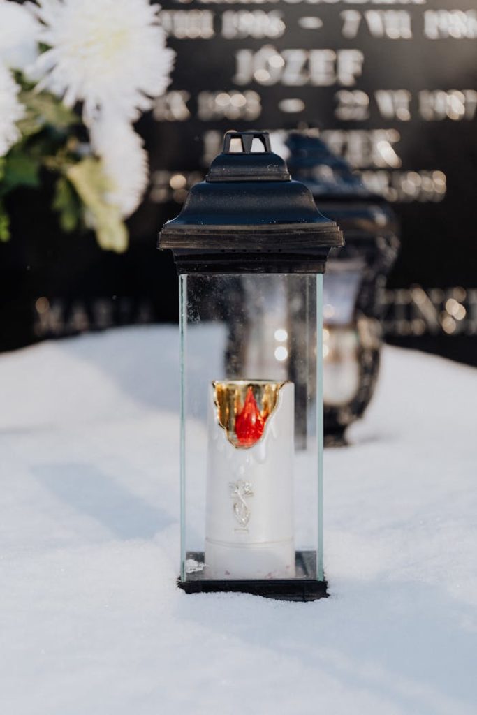 Grablicht auf einem schneebedeckten Grabstein Grablicht auf einem schneebedeckten Grabstein